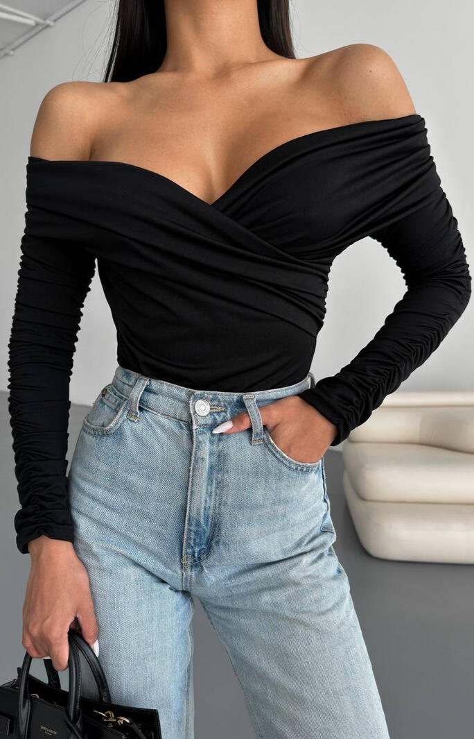 Модель у чорному топі з відкритими плечима та світлими джинсами — жіночий одяг оптом від виробника.